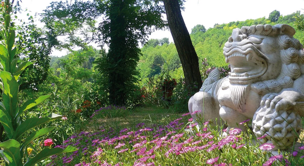 Steinskulptur zwischen Blumen im Garten